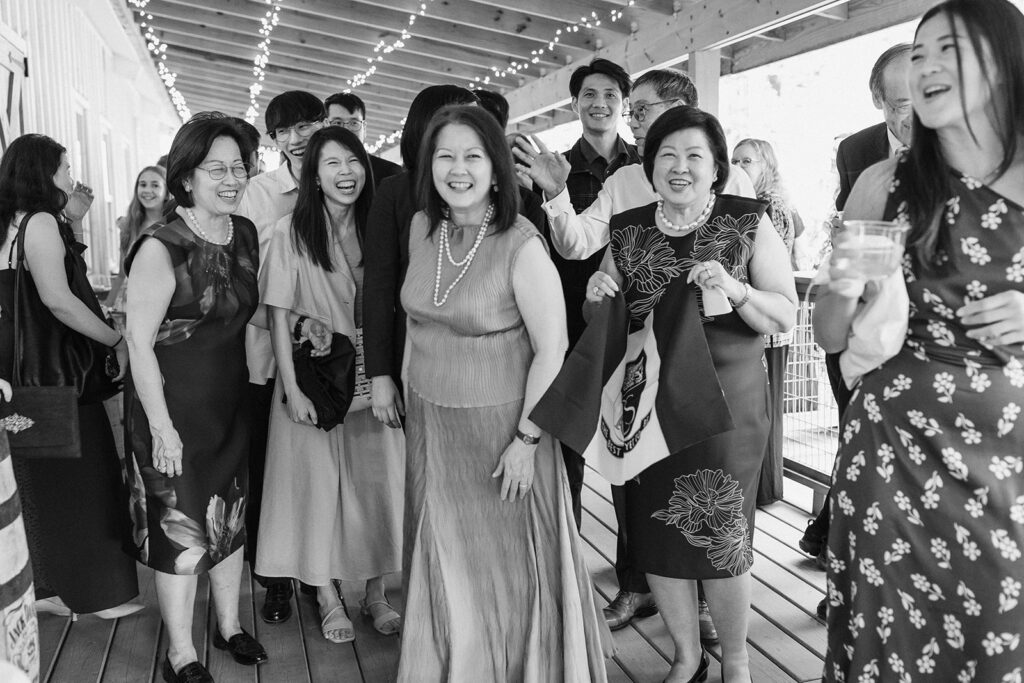 wedding guests smiling, gathered together outside underneath string lights